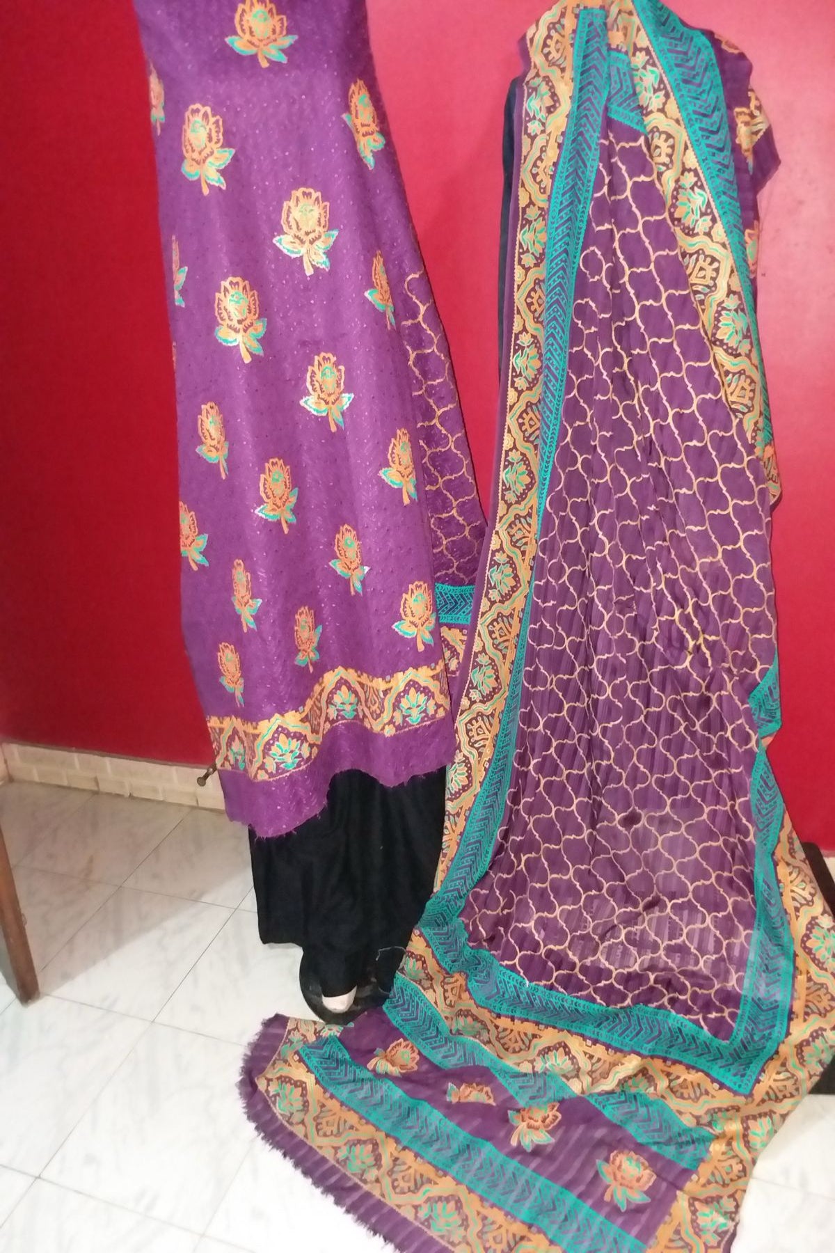 A 3-piece unstitched hand block print suit featuring a rich purple fine lawn shirt with gold and teal floral bootis and matching borders, paired with a patterned purple chiffon dupatta.