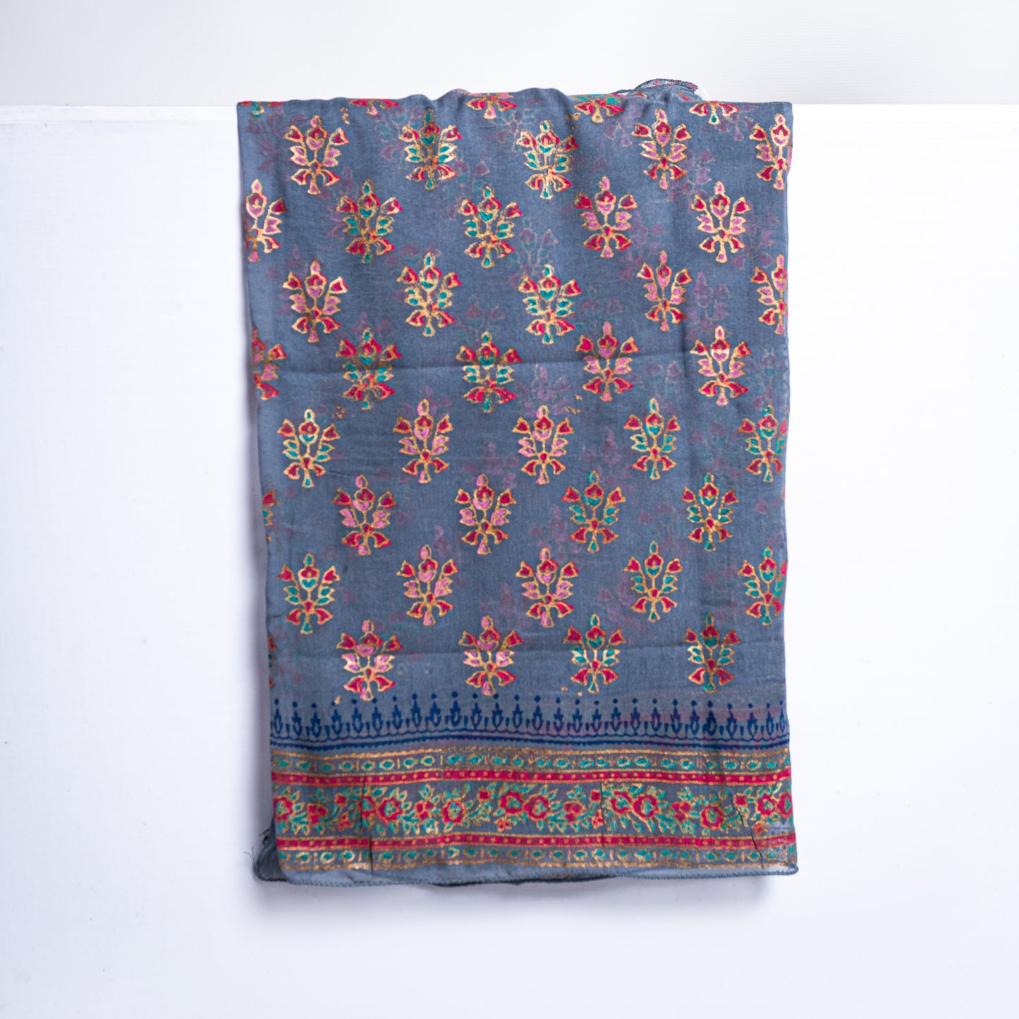 Close-up shot of traditional hand-block print patterns with intricate tilla work highlights on fine grey raw silk fabric for a designer unstitched suit
