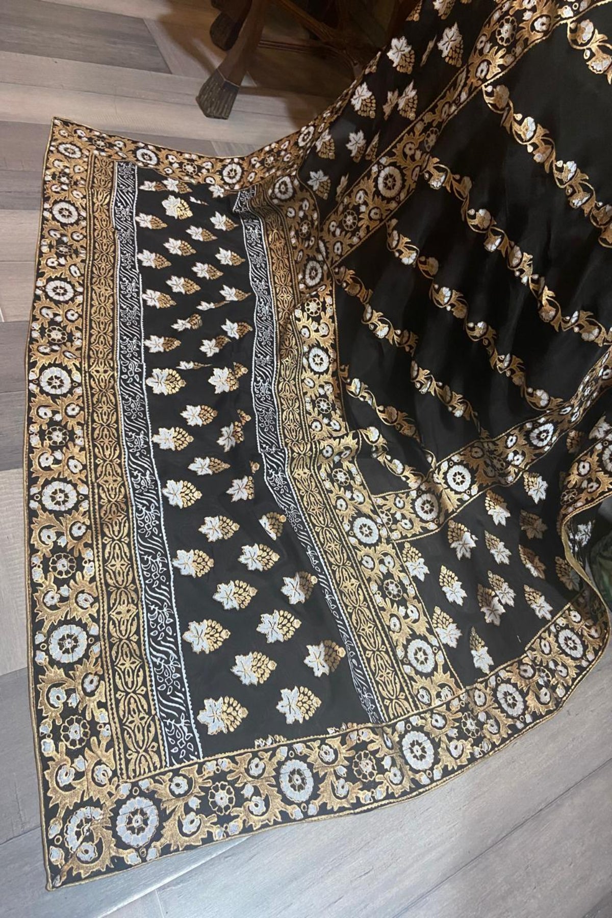 Full layout of 2.75 yards black silk dupatta with ornate gold and white motifs and four-sided golden massuri trim.
