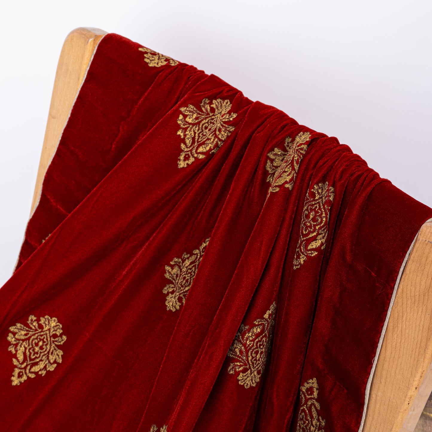 Elegant drape of a premium winter velvet shawl in maroon with shimmering gold prints for formal wedding wear