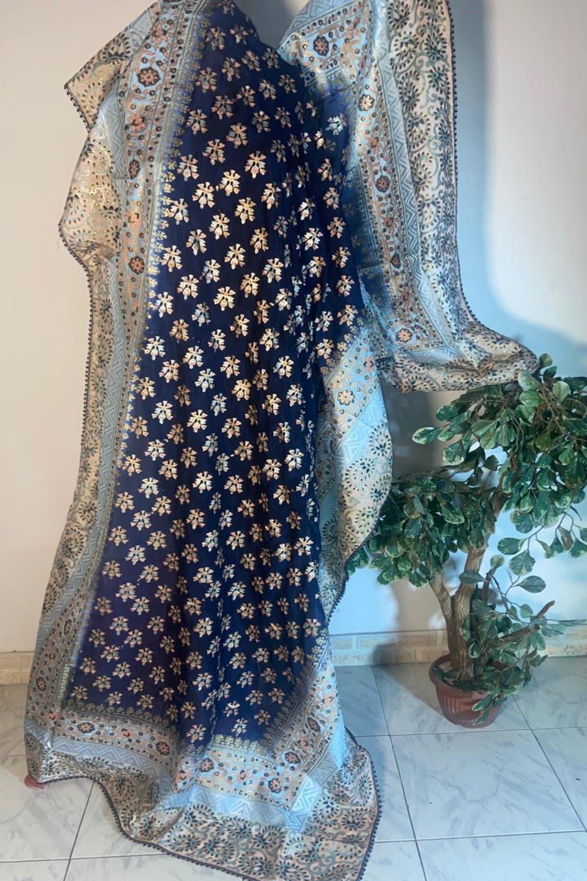 Close up of navy blue silk dupatta showing intricate gold foil block print and detailed massuri border.