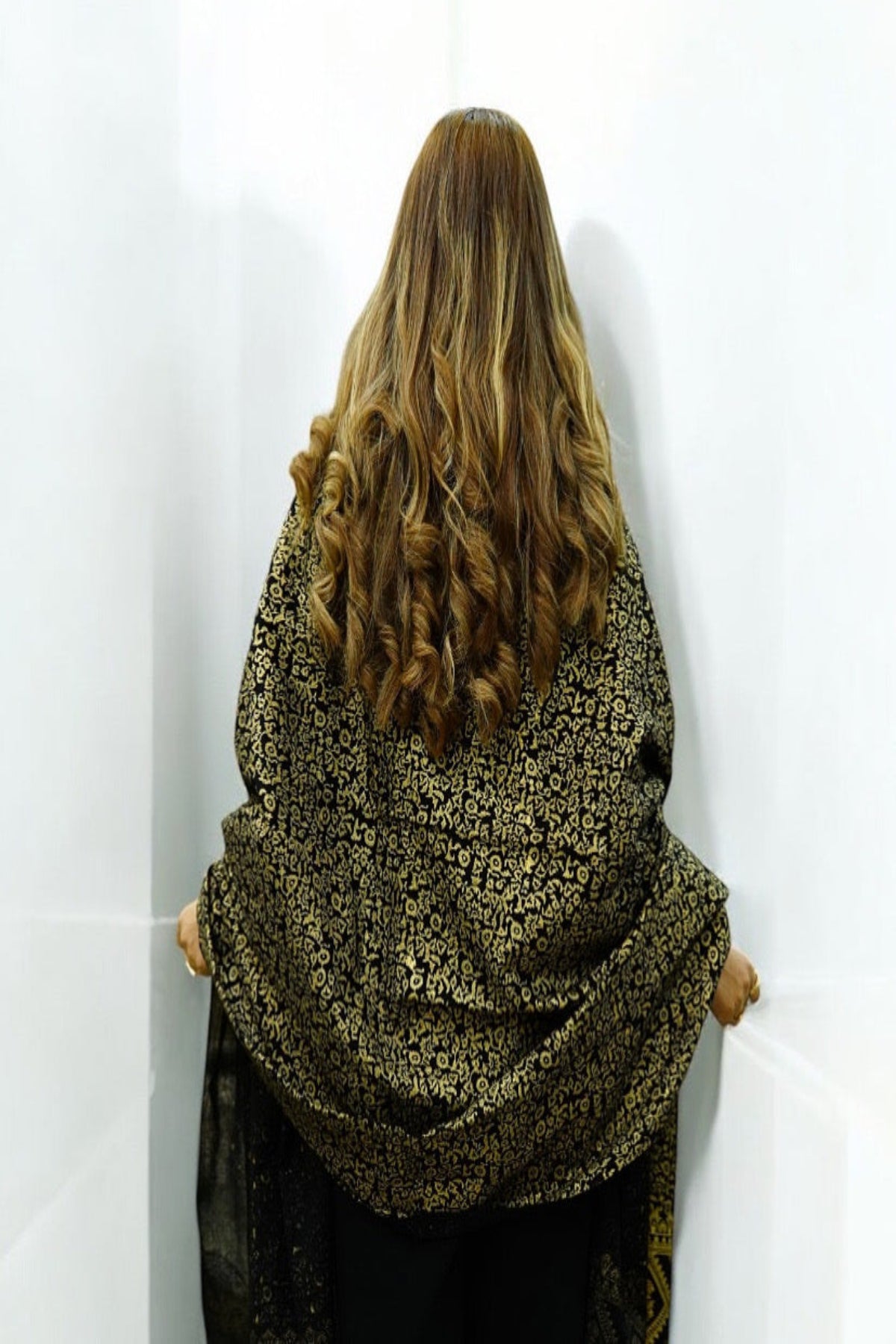 Back view of a woman showcasing a premium black luxury shawl with dense gold zari embroidery and intricate floral jacquard patterns.