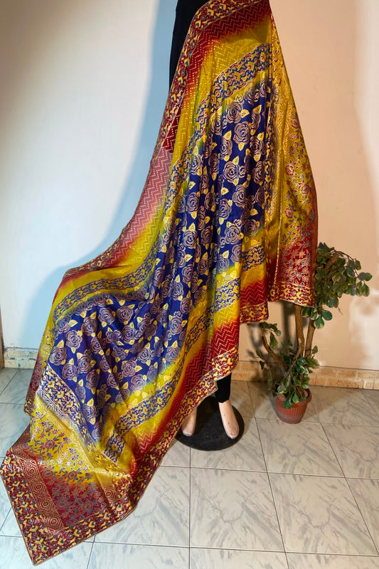 Vibrant multi-color raw silk dupatta featuring royal blue, mustard yellow, and red sections with gold floral block printing.