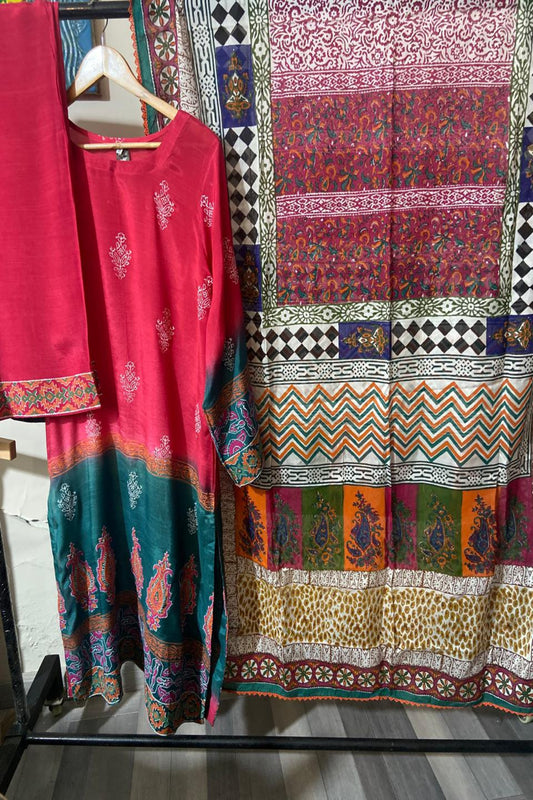 "A luxury 3-piece unstitched hand block print suit featuring a shocking pink and deep teal raw silk shirt with paisley motifs alongside a multi-colored geometric medium silk dupatta."