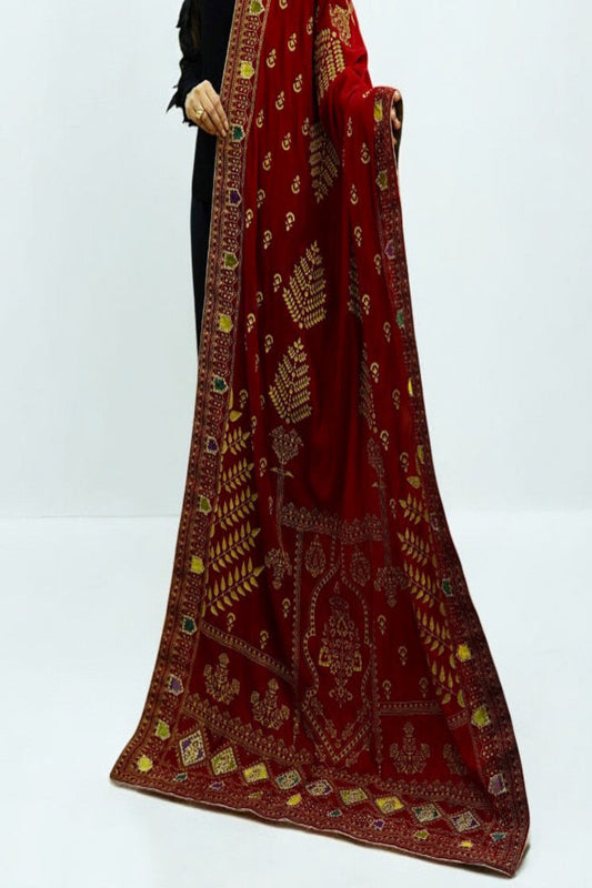 Flat lay view of a folded Zariyat red velvet shawl showcasing its satin inner lining, gold masoori borders, and traditional print.