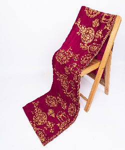  Close-up detail of traditional gold embroidery patterns on a luxury burgundy velvet fabric.
