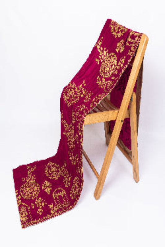 Burgundy velvet shawl with intricate gold embroidery draped over a wooden chair