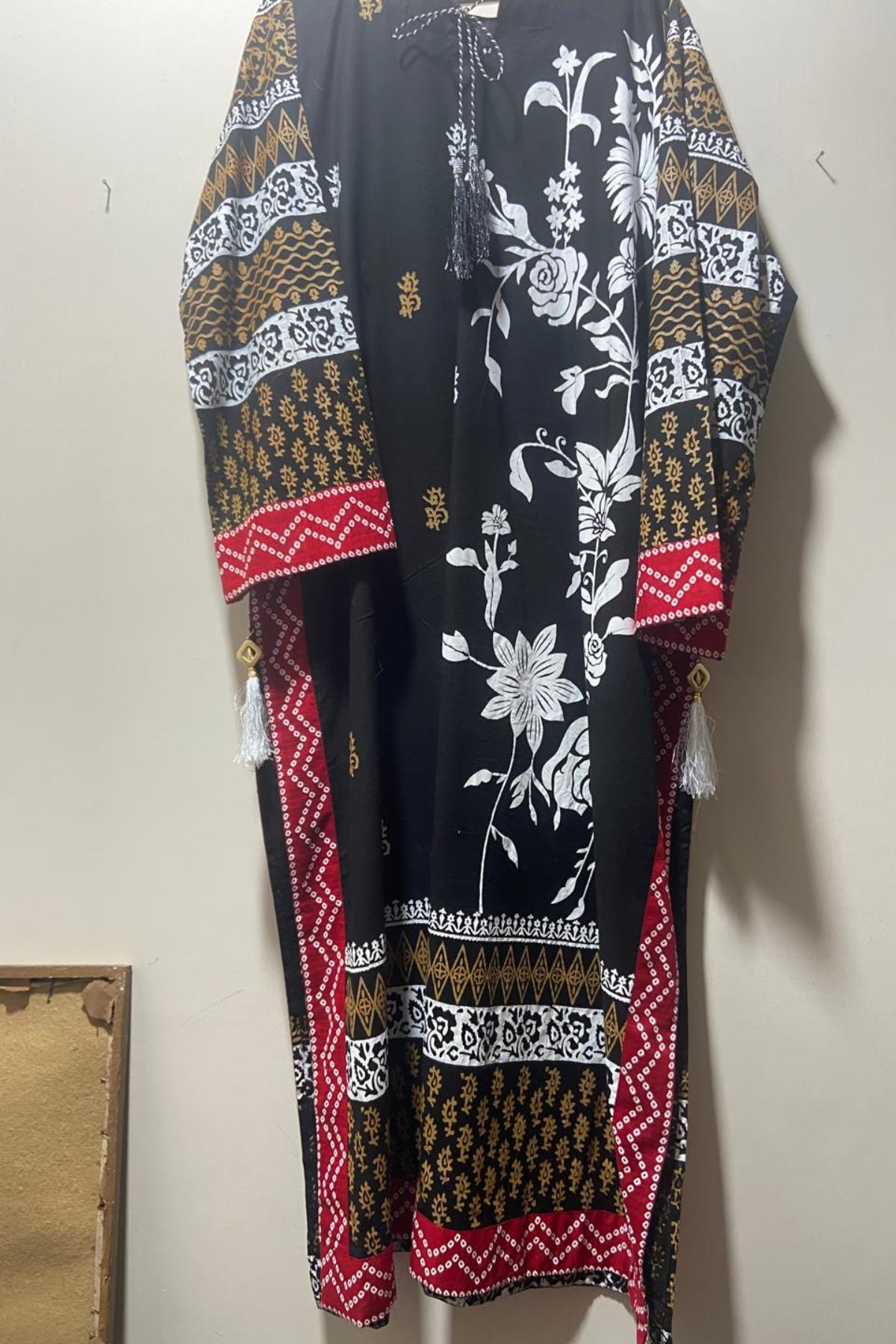 Hanger display of designer black block-printed long shirt with decorative neckline ties