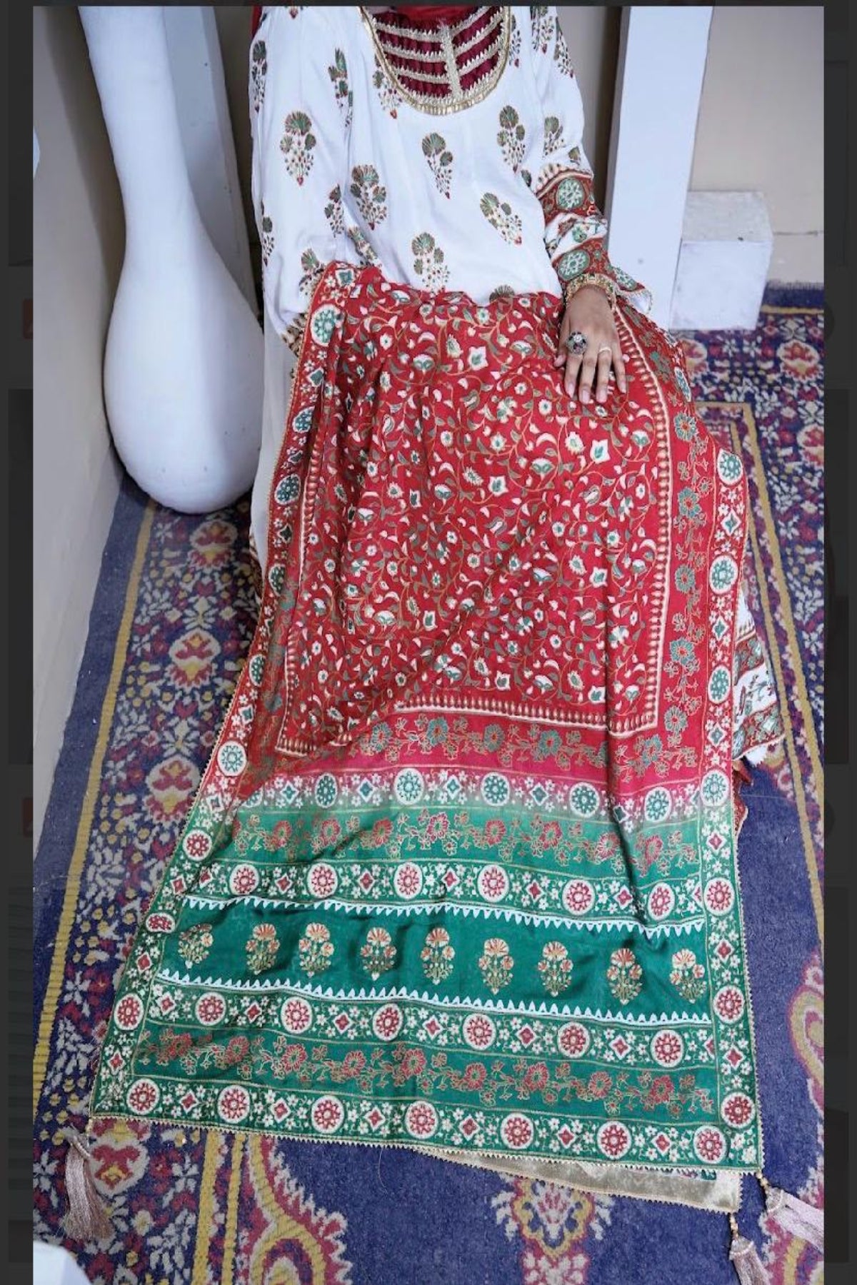 Model wearing the white raw silk block print kalidar frock with a rich red and green silk dupatta featuring golden zari borders and tassels