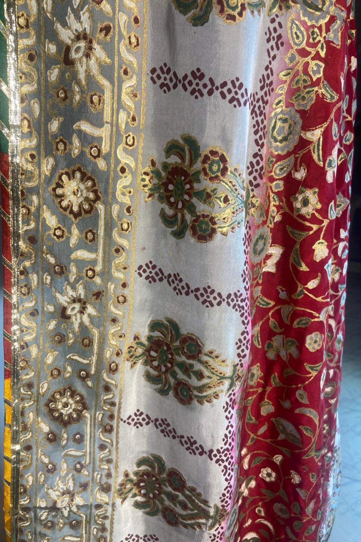 Close-up view of red silk dupatta featuring detailed gold block print and luxurious four-sided massuri lace