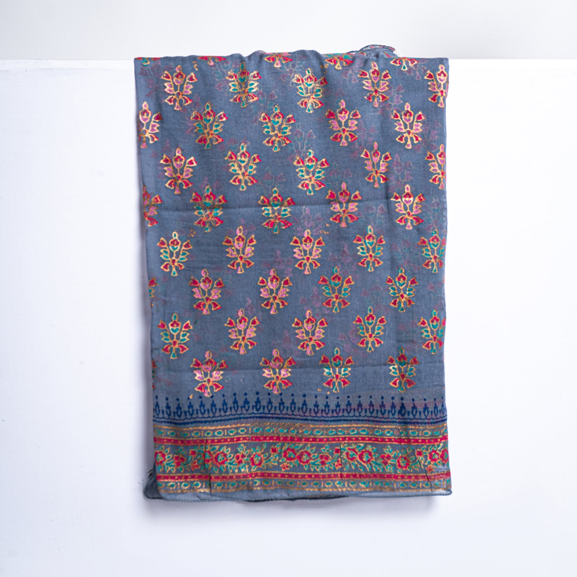 Close-up shot of traditional hand-block print patterns with intricate tilla work highlights on fine grey raw silk fabric for a designer unstitched suit