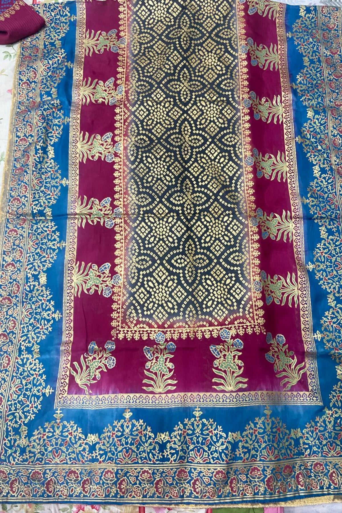 Flat lay view of a maroon and blue silk dupatta featuring intricate block-print geometric patterns and golden borders