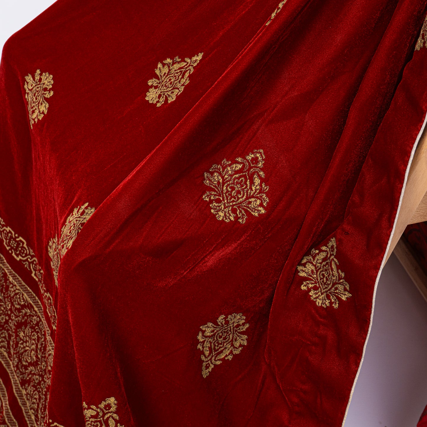 Close-up of golden screen printed traditional motifs scattered across rich maroon velvet fabric