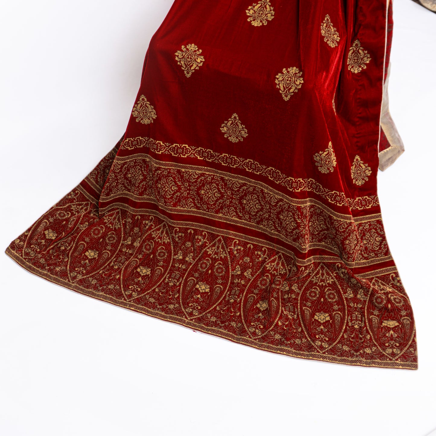 Close-up of a luxury maroon velvet shawl's heavily printed border with a golden masoori inner lay finishing