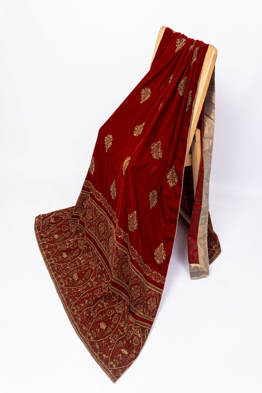 Premium maroon velvet shawl with heavy golden screen print border draped on a chair, showcasing luxury winter festive wear