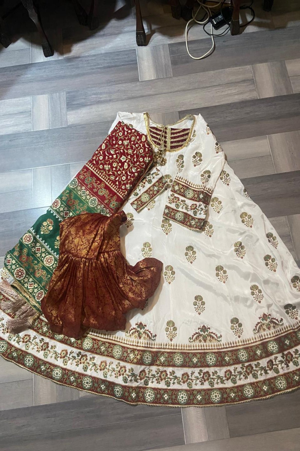 Full view of the white block print kalidar frock paired with a traditional red and green dupatta and optional Jamawar lehnga.