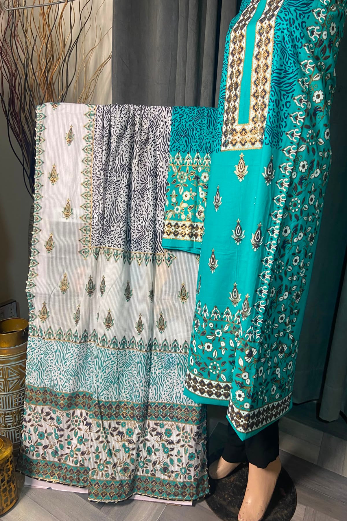 Turquoise and white printed unstitched 3-piece suit displayed on a mannequin showcasing the shirt, trousers, and dupatta.