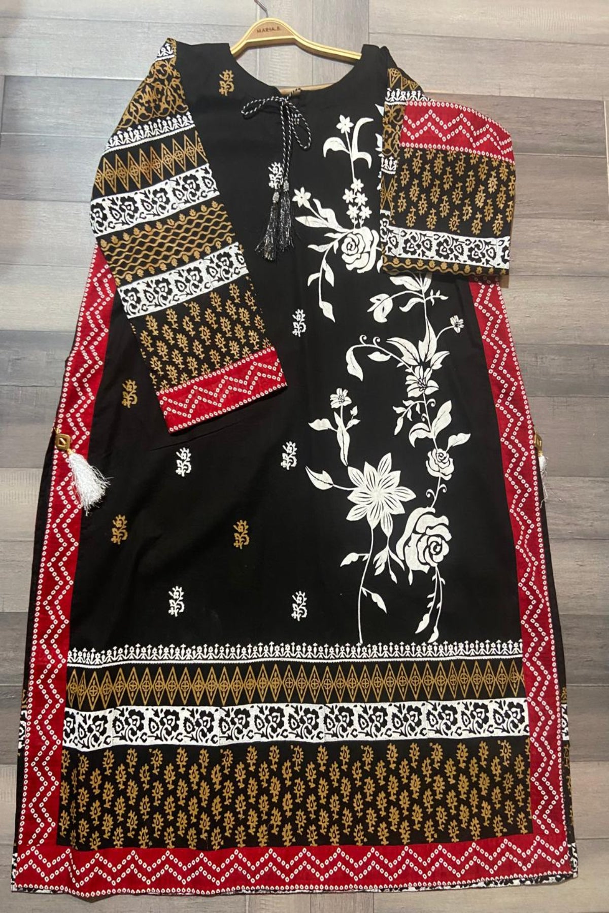 Full flat lay view of black lawn kurti showcasing intricate floral patterns and geometric borders.