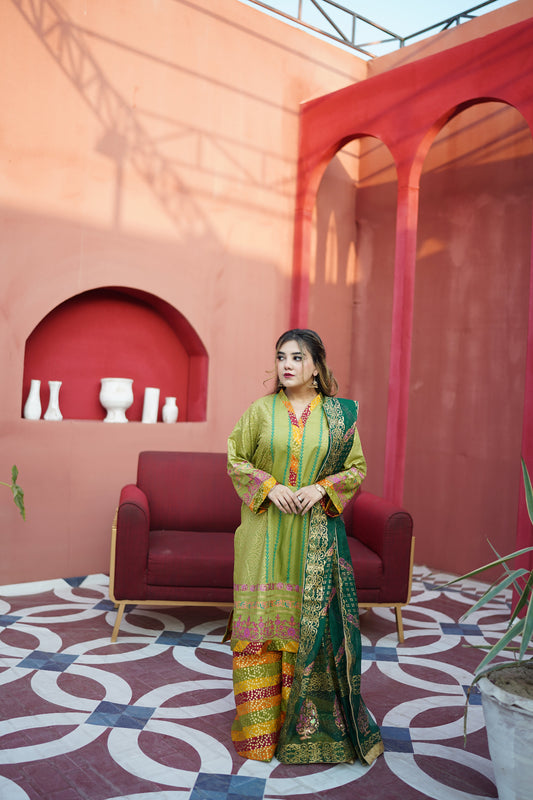 Woman in a colorful traditional outfit standing in a decorative indoor setting with red and pink walls.